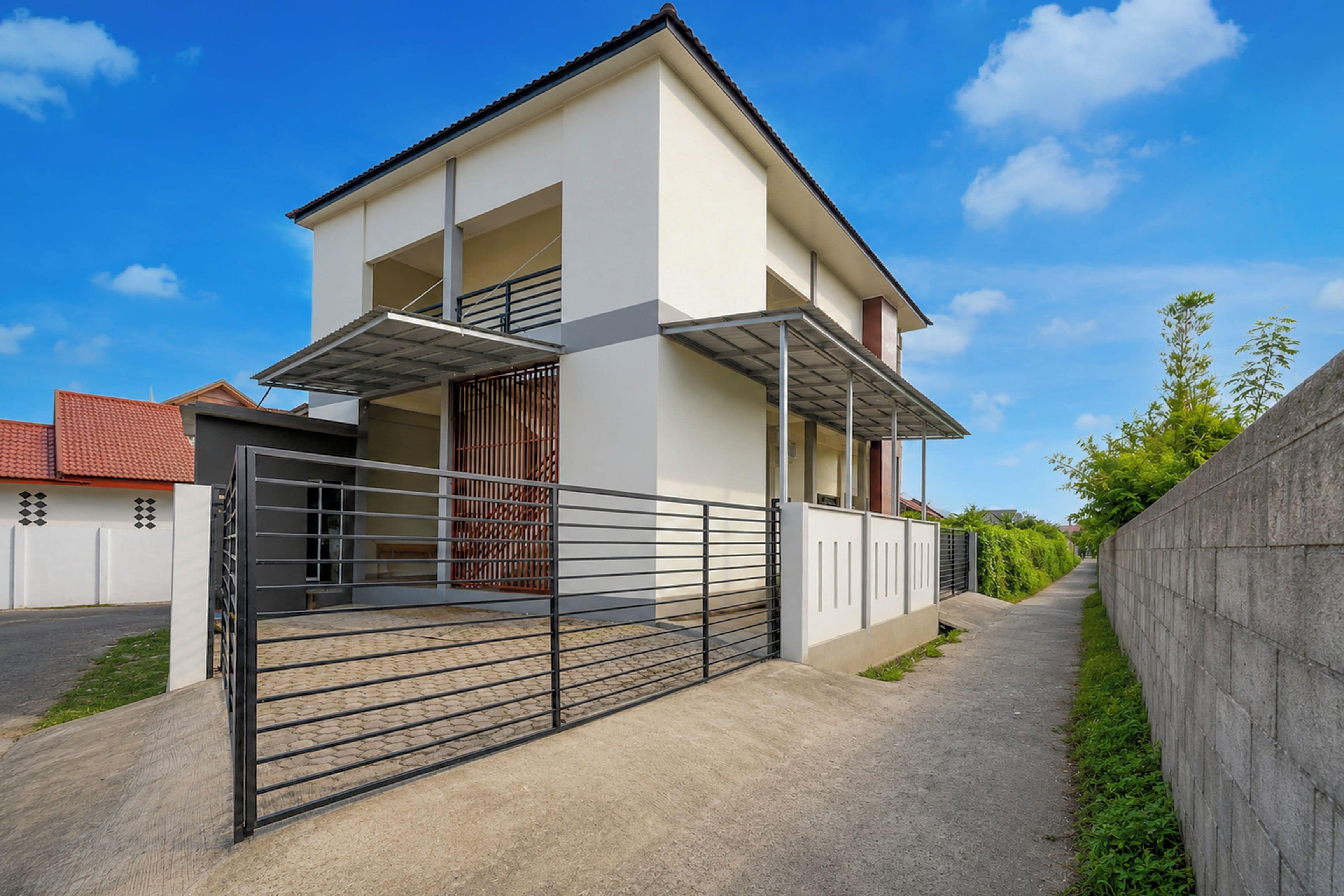Ein modernes, zweigeschossiges Haus mit überdachter Veranda, geschlossenem Eingangsbereich und befestigter Auffahrt.