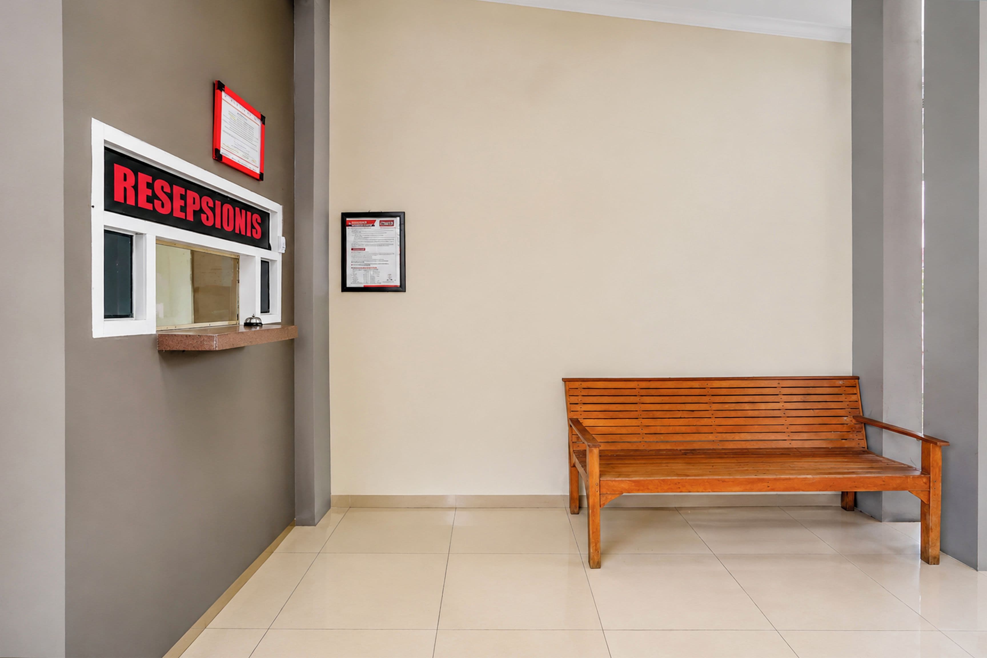 A reception area with a wooden bench, a reception desk, and two framed informational posters on the wall.
