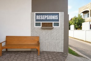 A bench outside a building with a sign that reads 'RESEPSIONIS'.