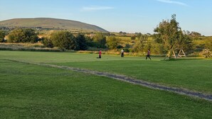 A grassy field with a clear sky, a hill in the distance, and a swing set. - Little Lake Lodge Retreat Sleeps 2 with Parking (Ballycastle)