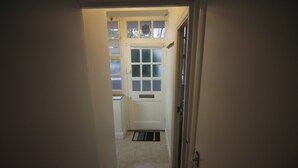 Een smalle gang die leidt naar een deur met een raam erboven.