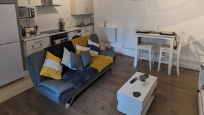 Een moderne woonruimte met een bank, eettafel en keukenhoek.