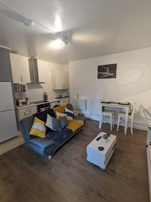 Ein modernes Wohnzimmer mit Sofa, Esstisch und Küchenbereich.