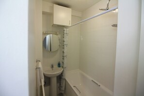 Un baño pequeño y blanco con bañera, lavamanos y espejo.