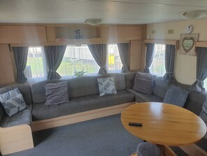Ein gemütliches Wohnmobil-Interieur mit einer Sitzecke, einem Holztisch und Vorhängen.