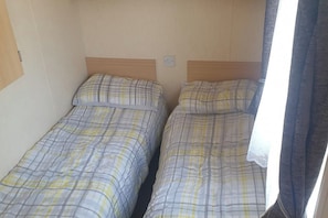 A room with two single beds, each with a headboard and a pillow. - 10 Berth Caravan Butlins Skegness Pet friendly (Skegness)