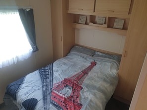 Ein Schlafzimmer mit einem Pariser Designbett, einem Holzschrank und einem Fenster mit Vorhang.