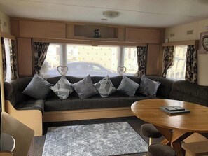A cozy RV interior with a sofa, a round table, and a view of the street outside. - 10 Berth Caravan Butlins Skegness Pet friendly (Skegness)