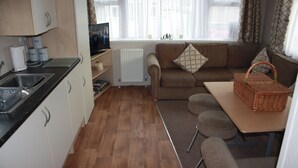 A compact kitchenette with a sink, tea and sugar dispensers, a small television, and a radiator. - 10 Berth Caravan Butlins Skegness 2 showers pets (Skegness)