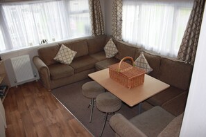 Ein gemütliches Wohnzimmer mit einem braunen Sofagarnitur, einem kleinen Tisch und einem Korbwäschesammler.