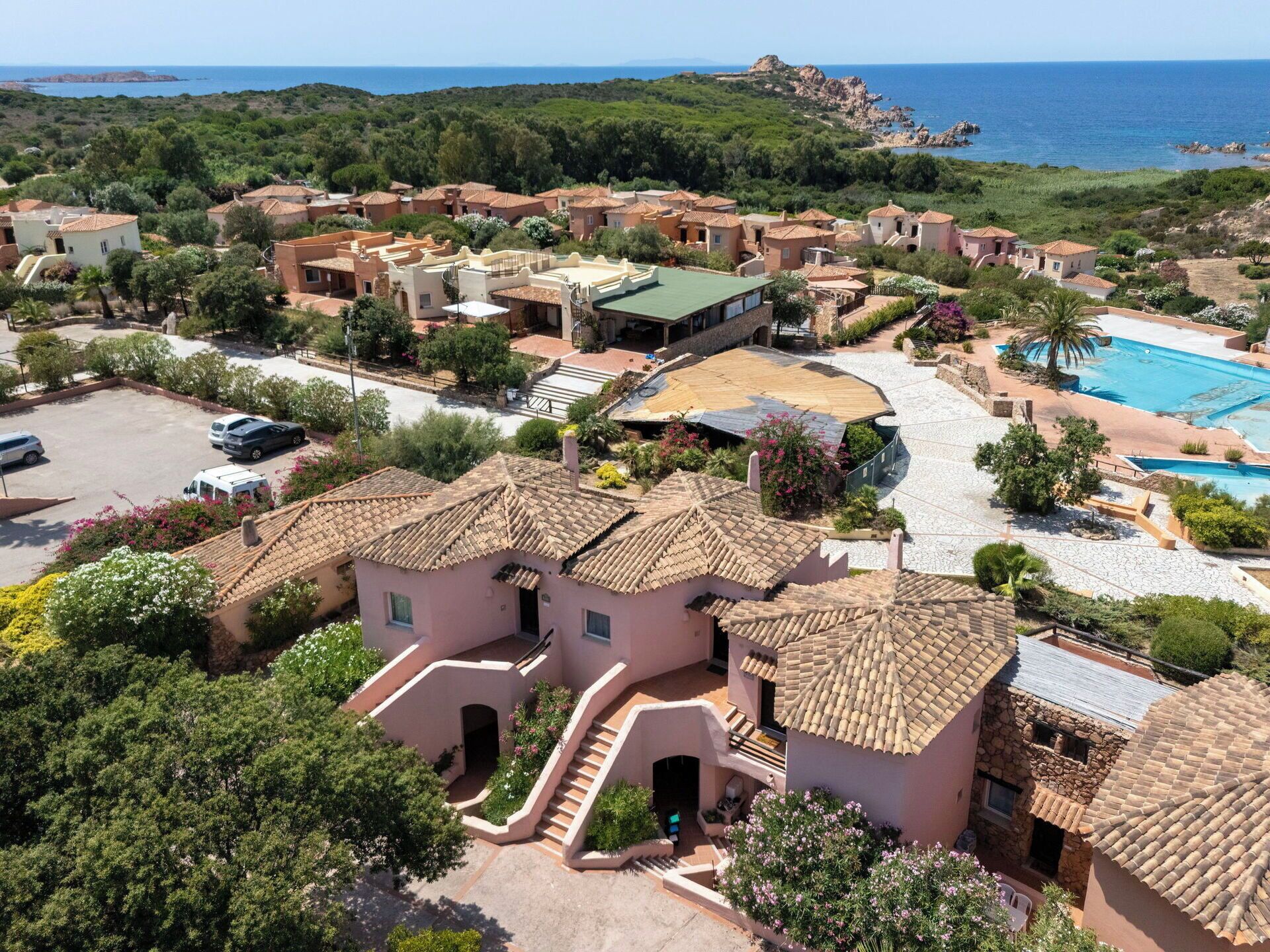 Una propiedad costera con varias villas, piscina y vista despejada al mar.