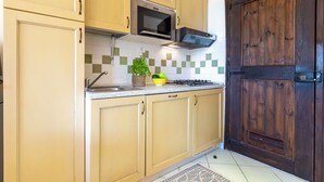 Une cuisine avec des armoires de couleur beige, un four à micro-ondes, une cuisinière et une porte en bois.