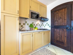 A kitchen with beige cabinets, a microwave, a stove, and a wooden door.