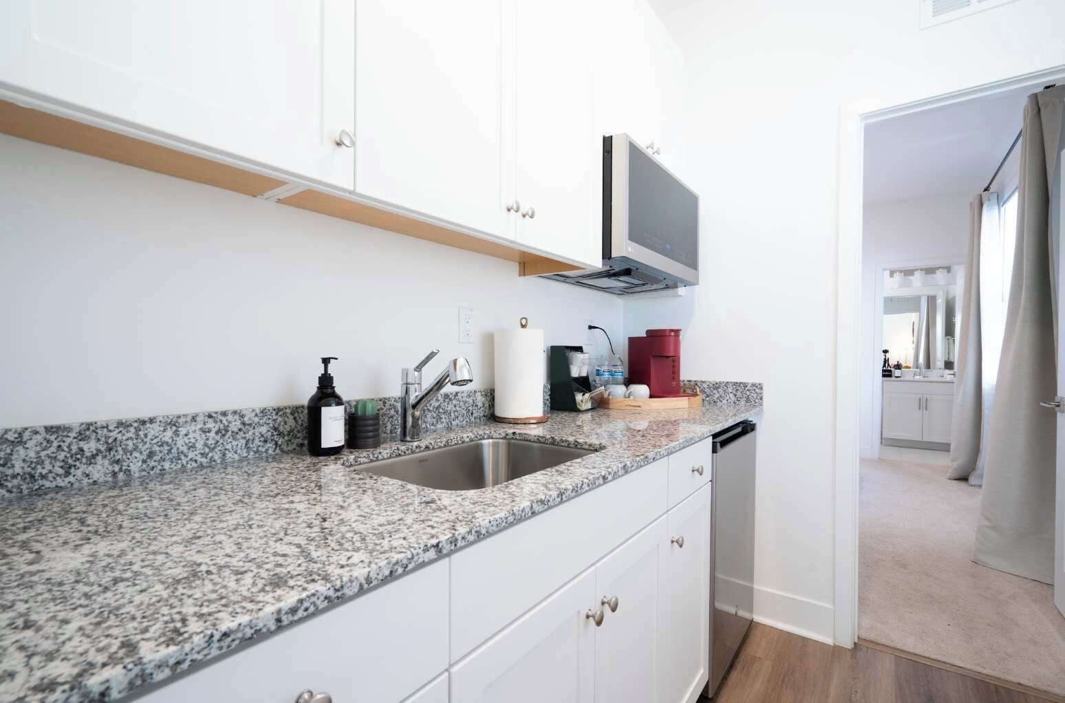A modern kitchen with granite countertops, stainless steel appliances, and white cabinetry.