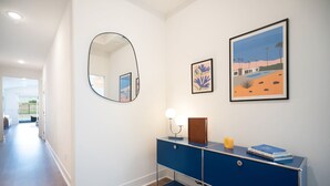 A hallway with a blue console, a round mirror, and two framed artworks on the wall. - Saltwater Pool, Spa & Casita  Terra Lago (Indio)