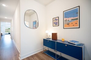 A hallway with a blue console, a round mirror, and two framed artworks on the wall. - Saltwater Pool, Spa & Casita  Terra Lago (Indio)