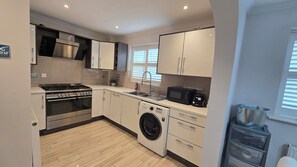 Een moderne keuken met roestvrijstalen apparatuur, een ingebouwde wasmachine en een compacte koelkast.
