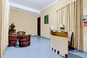 A reception area with a desk, chairs, and a decorative plant. - OYO 95377 Roemah Lawas (Yogyakarta)