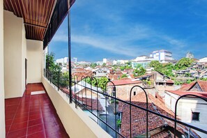 Un balcón con vistas a un paisaje urbano, que incluye edificios y zonas verdes.