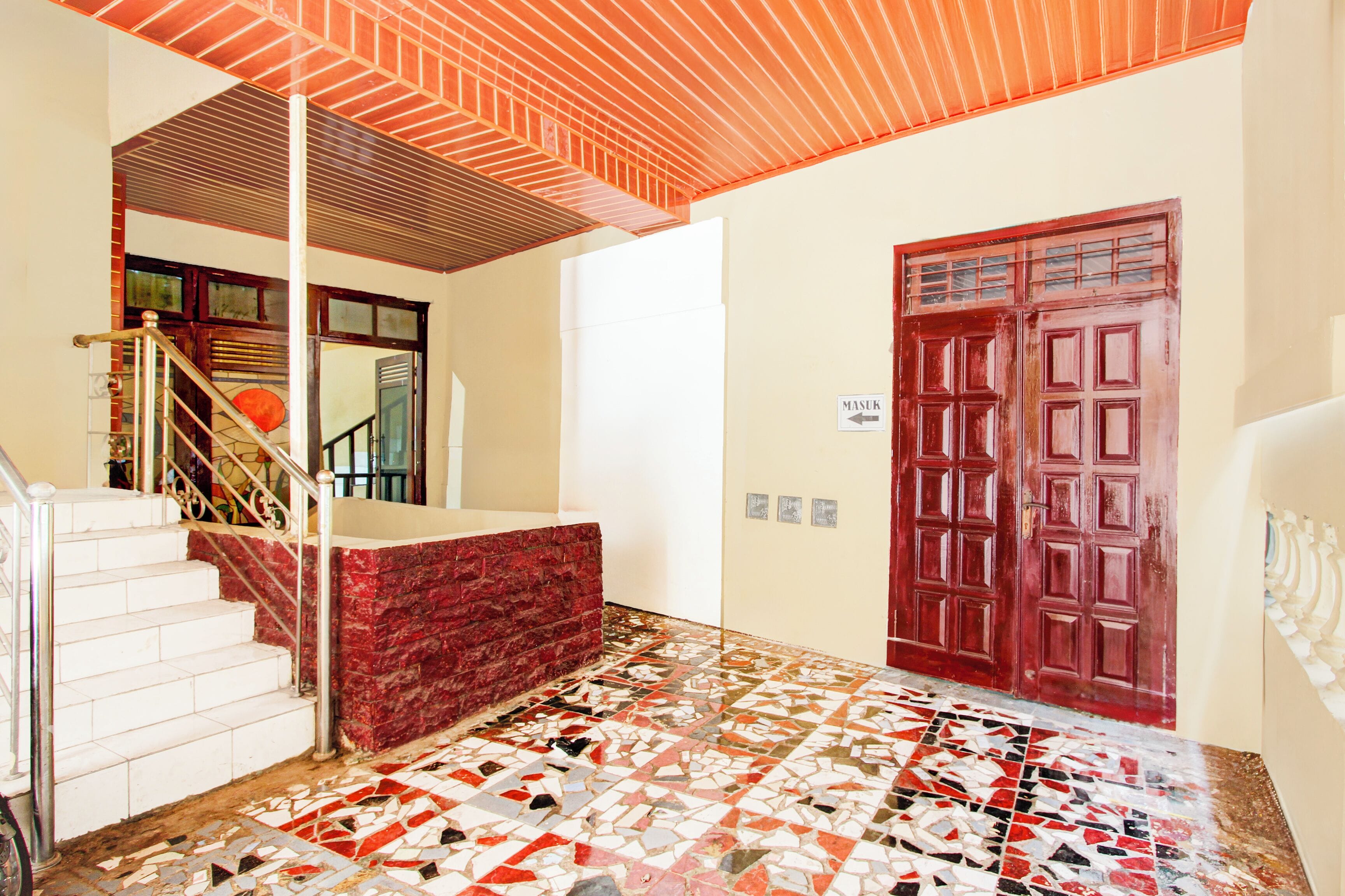 A staircase with a red carpet leading to a white door marked "MASUK".