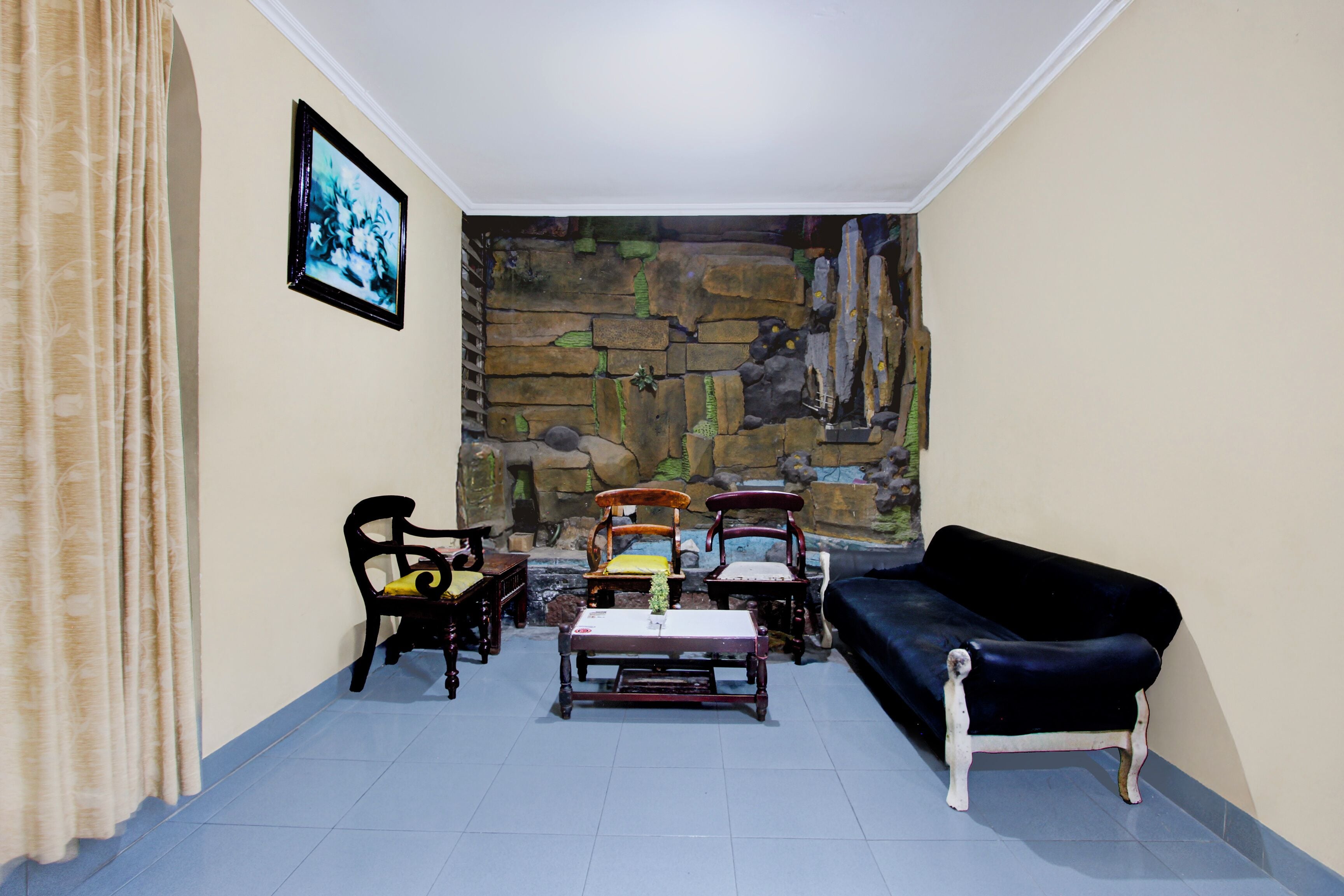 A living room with a stone wall mural, a black sofa, and wooden chairs.