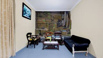A living room with a stone wall mural, a black sofa, and wooden chairs.