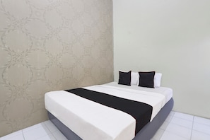 A neatly made bed with white and black bedding, a grey headboard, and a patterned wallpaper.