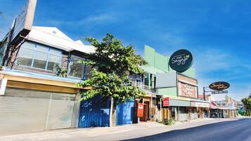 A street view with closed shops, a tree, and a clear blue sky.