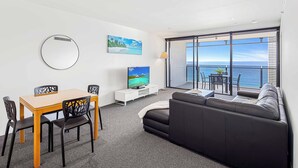 A modern living room with a dining area, a flat-screen TV, and a large window overlooking the sea. - Circle on Cavill Ocean View (Surfers Paradise)