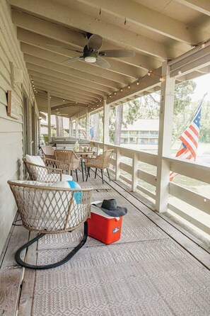 A covered porch with wicker chairs, a table, and a ceiling fan. - Villa Bandido-Golf Course, Pool, Tennis Court, Pet Friendly, & Golf Cart Deals (Miramar Beach)