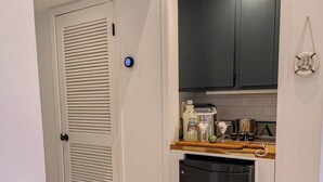 Una cocina compacta con lavavajillas, microondas y una pequeña encimera con diversos objetos.