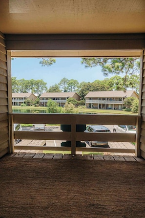 A view from a room with a large window overlooking a parking area and buildings. - Villa Bandido-Golf Course, Pool, Tennis Court, Pet Friendly, & Golf Cart Deals (Miramar Beach)