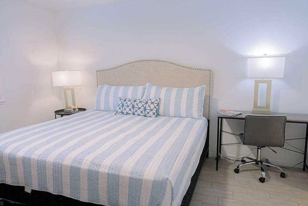 Une chambre d’hôtel comprenant un lit, un bureau avec une chaise et deux lampes de chevet.