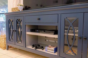 Ein graues Schranksystem mit Glastüren, ein Regal mit einer Spielkonsole und ein kleines Spielzeugauto.