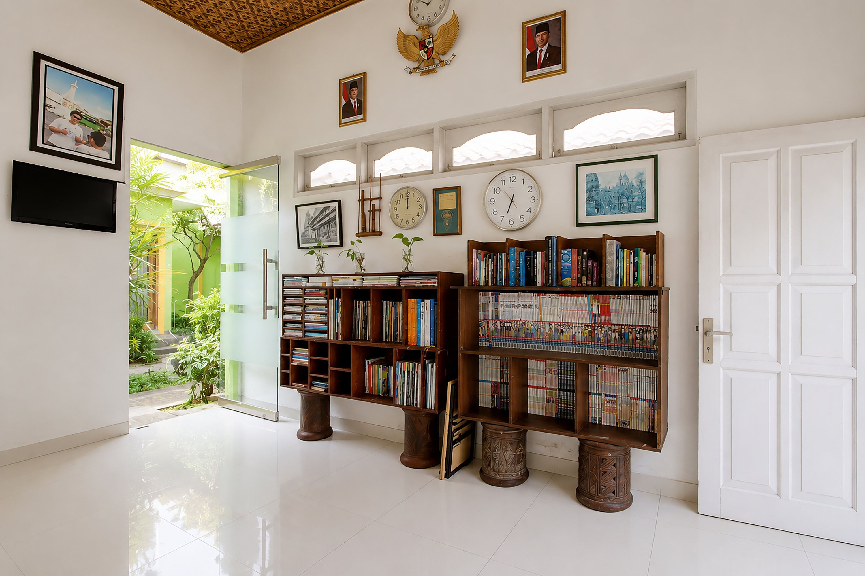 Una habitación amplia con una gran estantería, un reloj de pared y cuadros enmarcados.