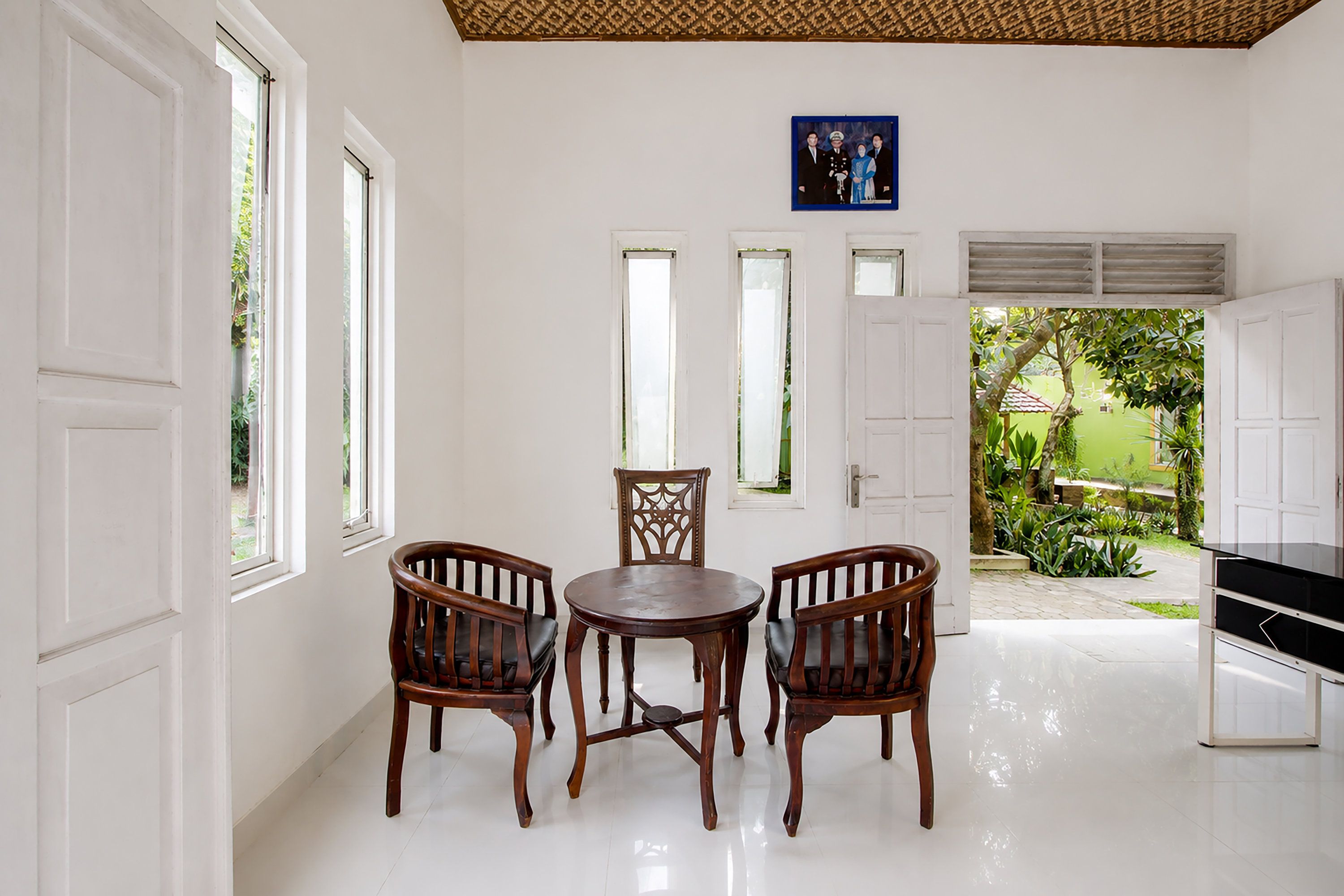 A room with a dining table and chairs, a picture on the wall, and a view of the outside.