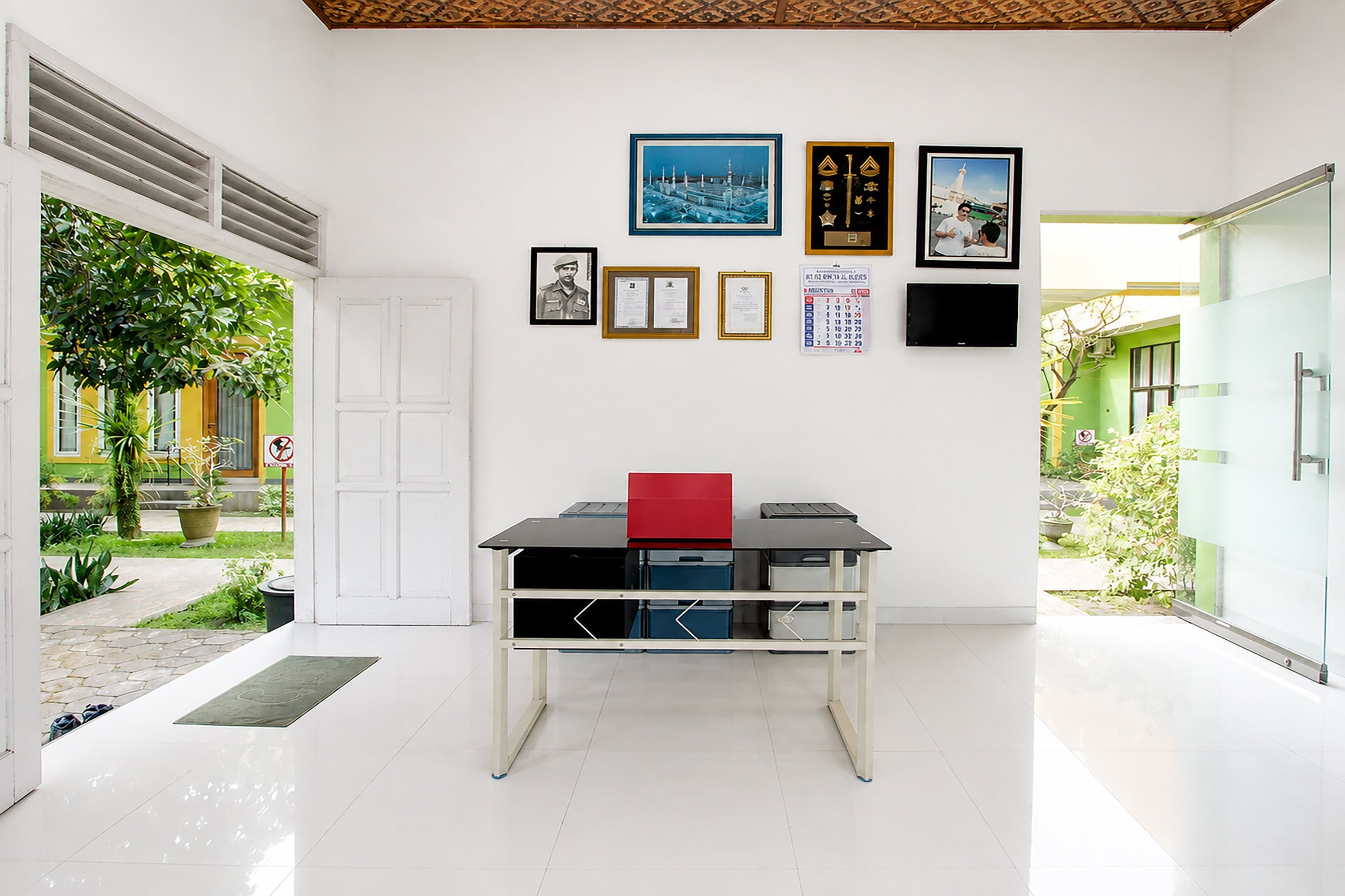 A modern office space with a desk, computer, and various framed items on the wall.