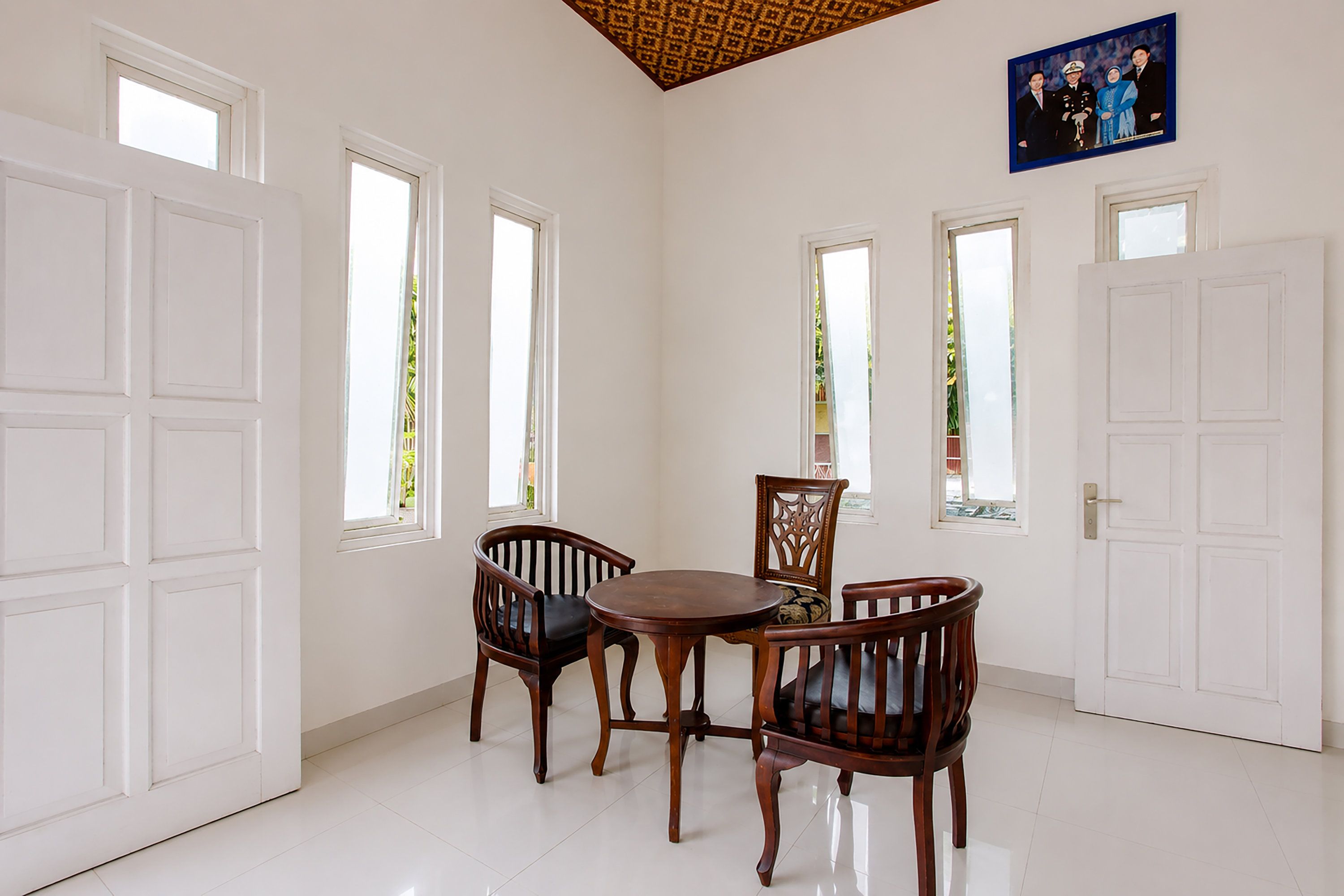 Una habitación con paredes blancas, una mesa de comedor de madera con sillas y una foto enmarcada en la pared.