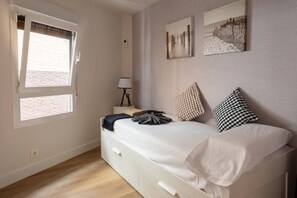 A bedroom with a bed, a nightstand, a lamp, and two wall-mounted pictures. - Geure portue etxea, wonderful sunrise (Bermeo)