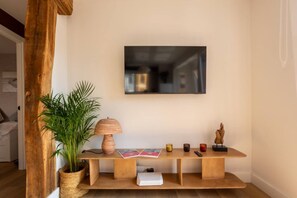 A wooden console table with a lamp, a potted plant, and a flat-screen TV mounted on the wall. - Geure portue etxea, wonderful sunrise (Bermeo)