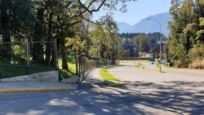 A curved road with a sidewalk, trees, and a mountain in the background. - Apartment in Alicura - Puc ón (Pucon)