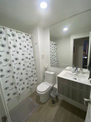 Ein Badezimmer mit Toilette, Waschbecken und einer Duschvorhang mit Augenmustern.