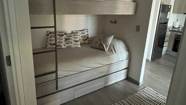 A bunk bed with a ladder, a pillow, and a patterned pillow on the lower bunk. - Apartment in Alicura - Pucón (Pucon)
