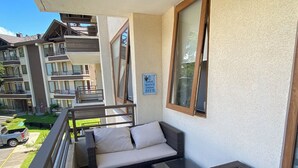 A balcony with wicker furniture, a sign promoting water conservation, and a view of a multi-story building. - Apartment in Alicura - Pucón (Pucon)