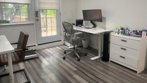 Een kamer met een bureau, stoel, computer en opbergruimte.