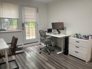 Ein Zimmer mit Schreibtisch, Stuhl, Computer und Stauraum.