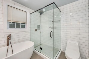 Un baño con ducha envuelta en vidrio, una bañera blanca y un inodoro.