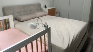 Een slaapkamer met een bed, nachtkastje, lamp en een kledingkast.
