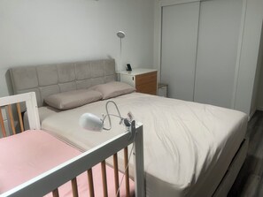 Ein Schlafzimmer mit Bett, Nachttisch, Lampe und Kleiderschrank.