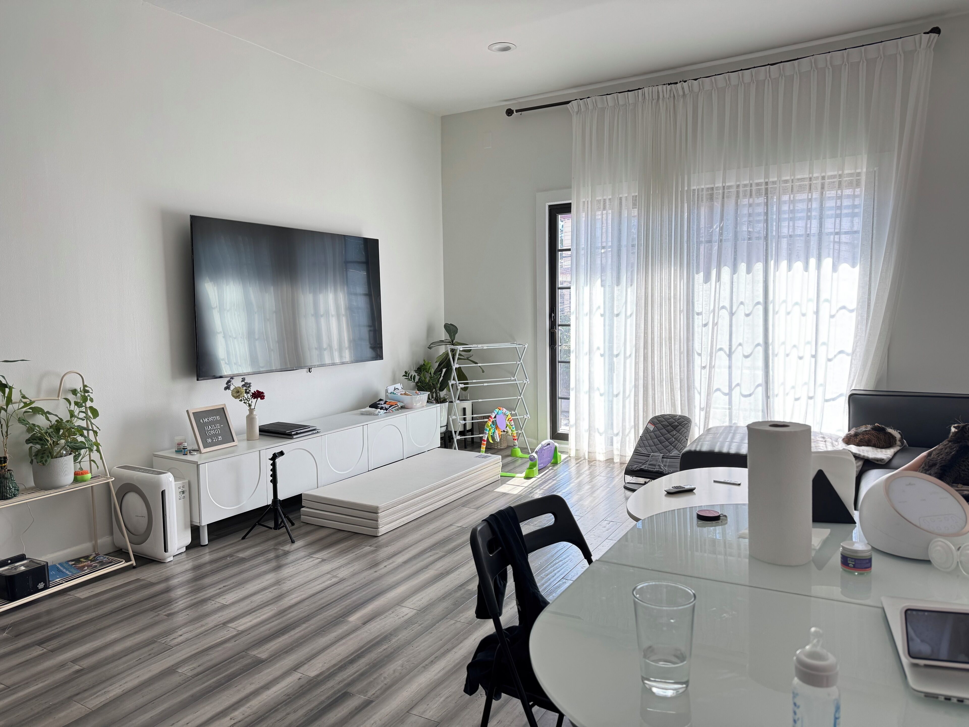 A modern living room with a flat-screen TV, a dining table, and a sofa.